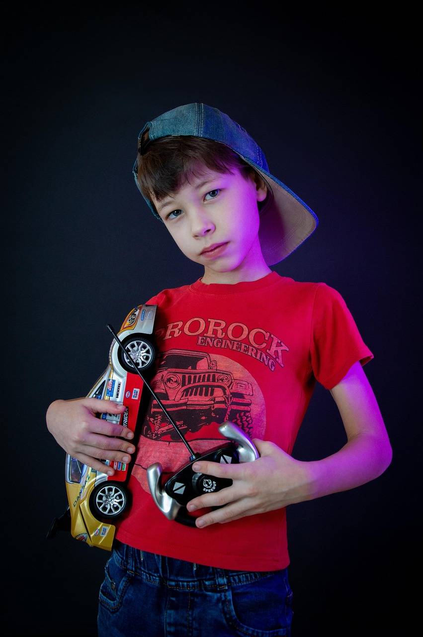 boy, machine, toy, remote control, radio controlled toy, joystick, childhood, baseball cap, t-shirt, baby, machine on the remote control, remote controller, toy car, t-shirt with a car